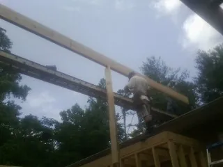 Carpenter setting a ridge beam over a new addition frame — Ice Dam Removal by Roofing Brothers in Micro