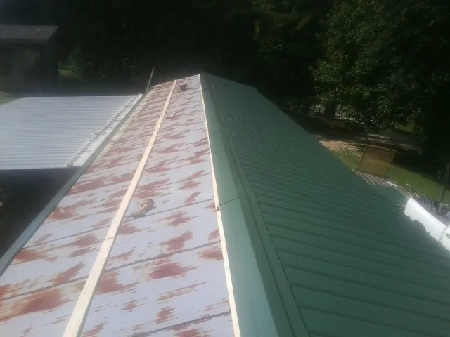 Old rusted panels beside newly installed green metal roofing — Wind Damage Roof Repair by Roofing Brothers in Micro