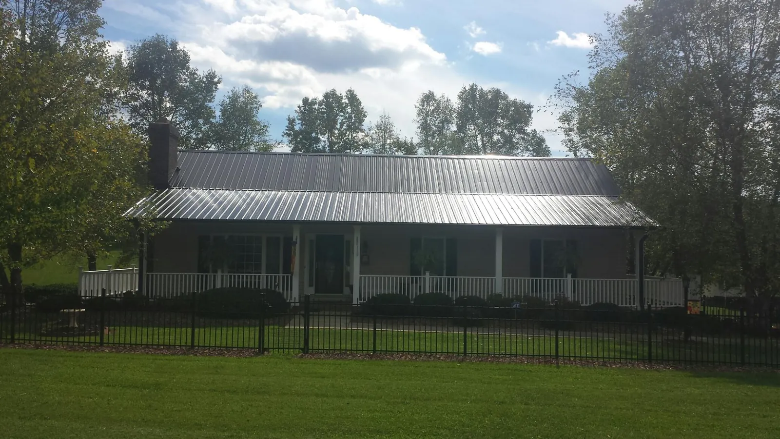 Gray metal roof on a brick ranch with a full width front porch — Gutter Guard Installation work by our crew in Micro